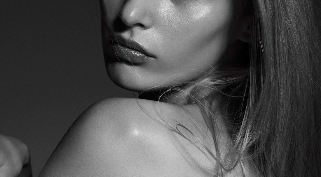 Black-and-white close-up of a woman’s cheek, lips and neck showing natural skin texture.